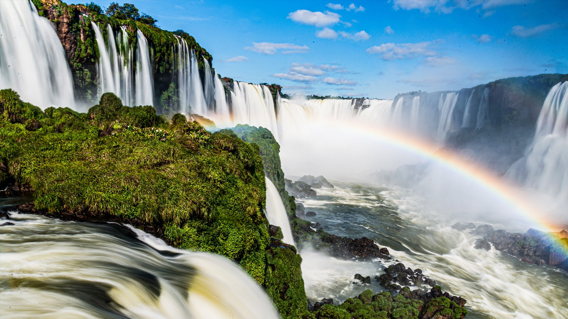 Iguaçu Falls surrounded by lush vegetation and a rainbow